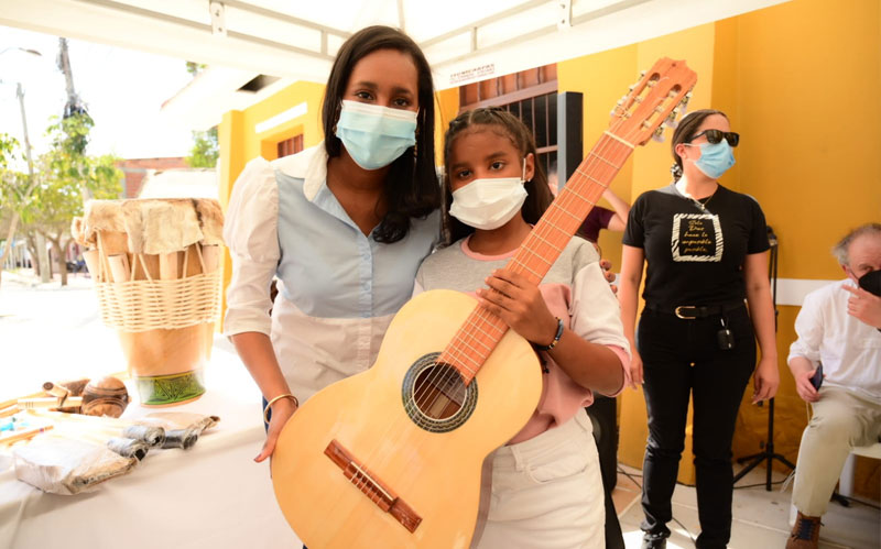 Fotografía Ministra de Cultura con Niña recibiendo instrumento